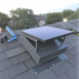 A Remington Solar attic fan being installed on a roof.