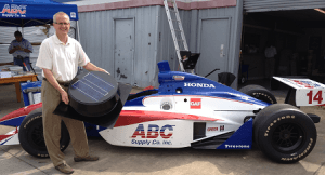An ABC Supply racecar, with a man holding a Remington Solar attic fan.