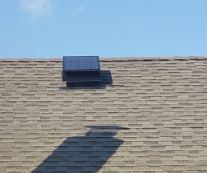 Front view of a Remington Solar attic fan on a roof with the blue sky in the background.